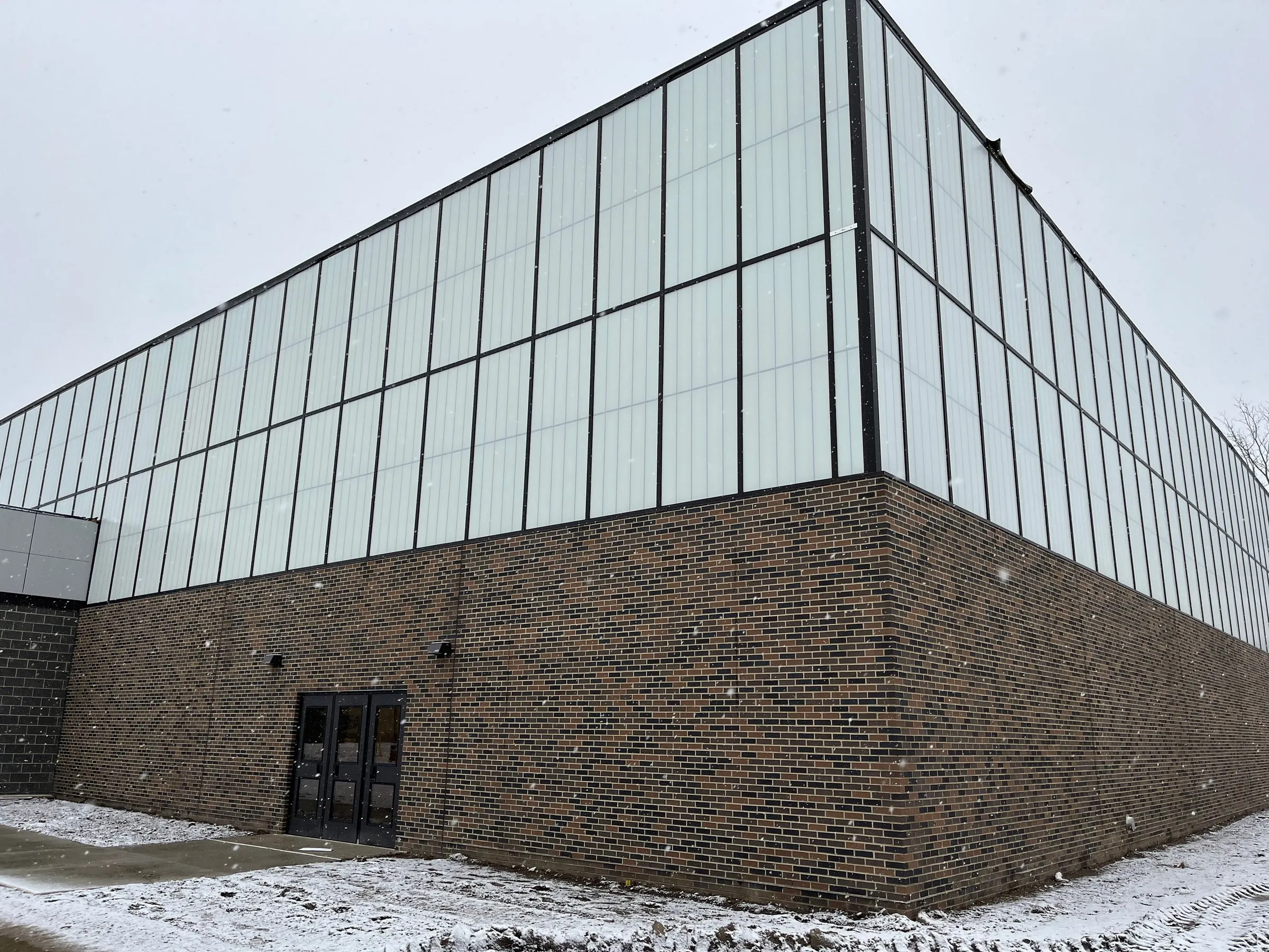 Glass curtain-wall gym addition at Pontiac High School under a winter sky
